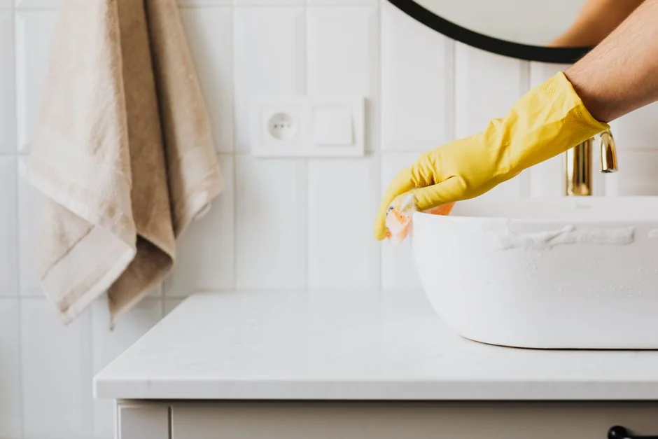 why-choose-us Une femme portant une chemise à carreaux nettoie un plan de travail de cuisine avec un vaporisateur et un chiffon.